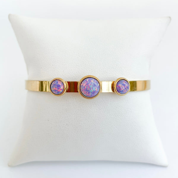 Gold bracelet with purple gemstones on a white cushion