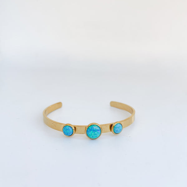 Gold bracelet with three turquoise stones on a white background