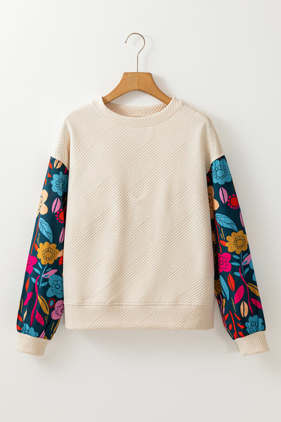 Cream sweatshirt with colorful floral sleeves on a wooden hanger against a white background