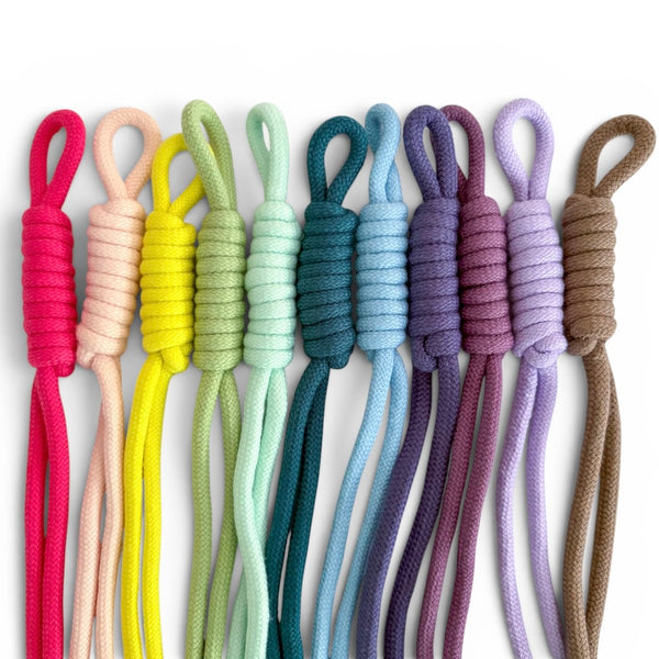 Nine knotted braided cords in assorted colors, including pink, peach, yellow, mint green, teal, light blue, purple, mauve, lavender, and brown, arranged vertically on a white background.
