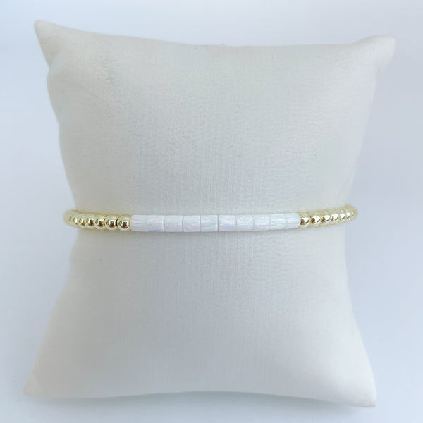 white opal beaded bracelet with gold accents on a white pillow