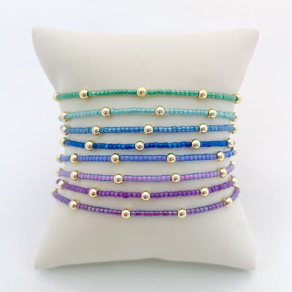 Set of colorful beaded bracelets on a white cushion