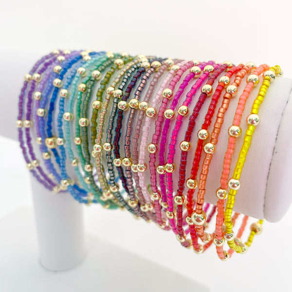 Row of colorful beaded bracelets on a white stand