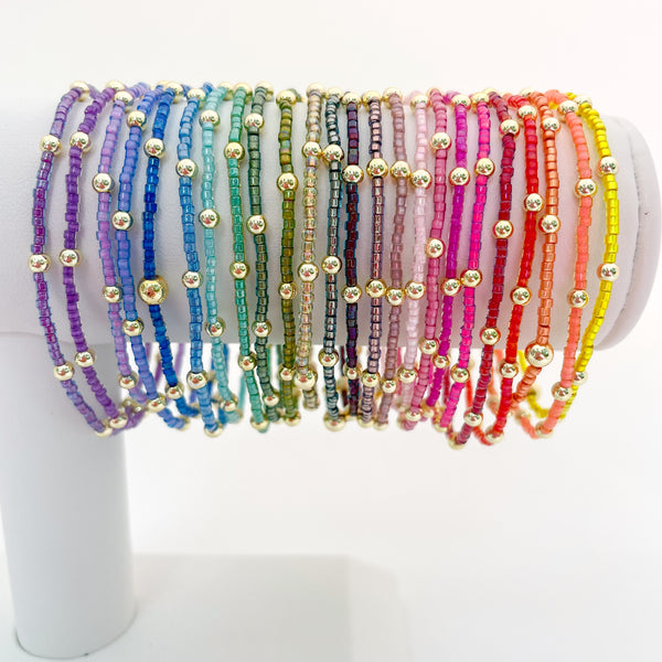 Set of colorful beaded bracelets on a white stand