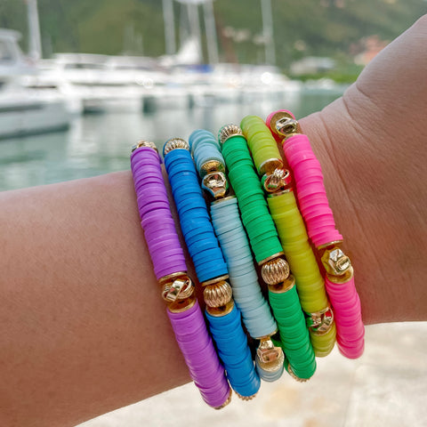 Colorful bracelets on a wrist with a blurred background of boats and water.