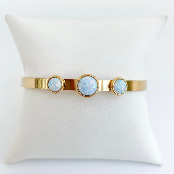 Gold bracelet with three opal stones on a white cushion