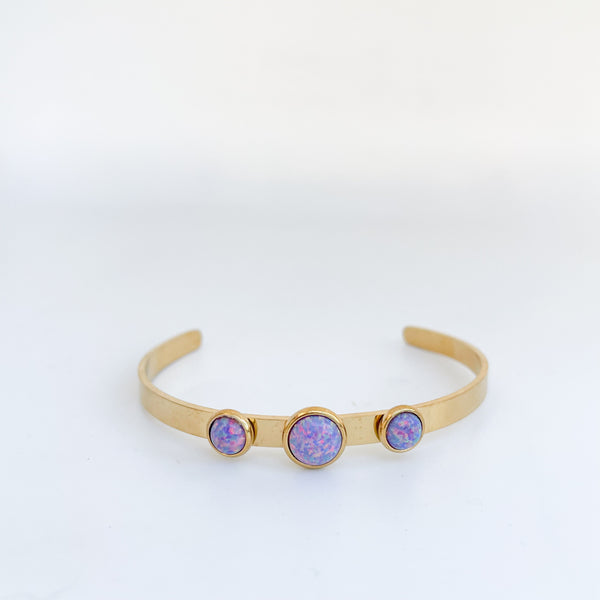 Gold bracelet with three purple gemstones on a white background