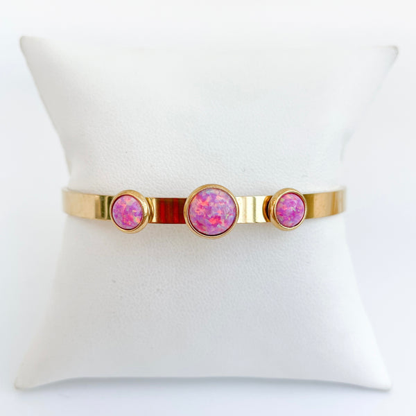 Gold bracelet with pink gemstones on a white cushion