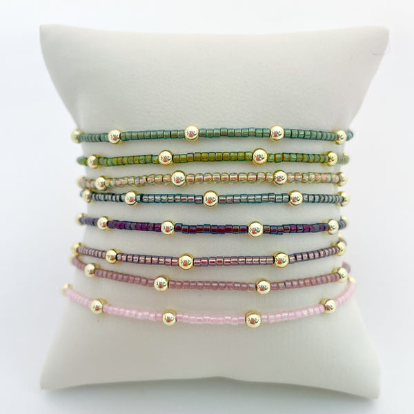 Set of beaded bracelets on a white cushion with a white background