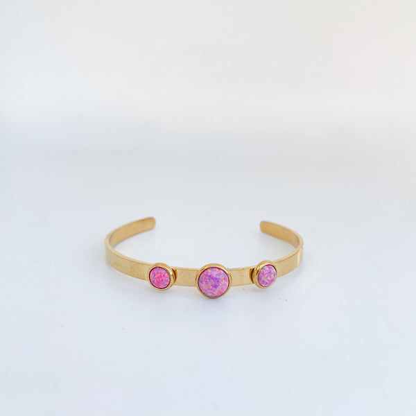 Gold bracelet with pink gemstones on a light gray background