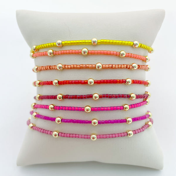 Set of colorful beaded bracelets on a white cushion