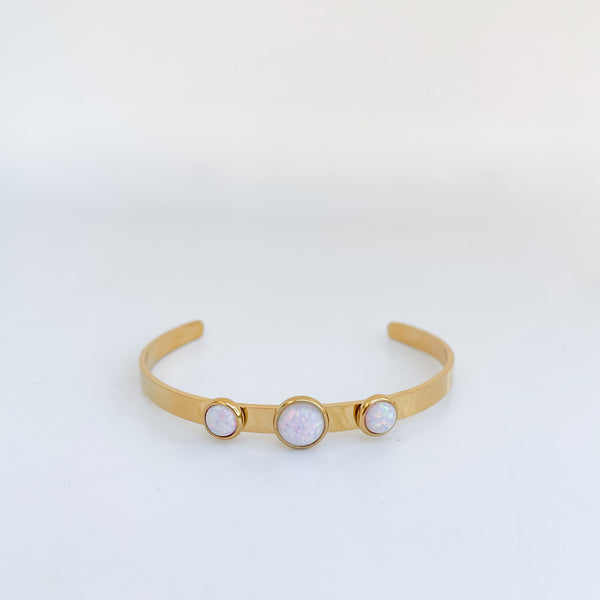 Gold bracelet with three circular stones on a light gray background