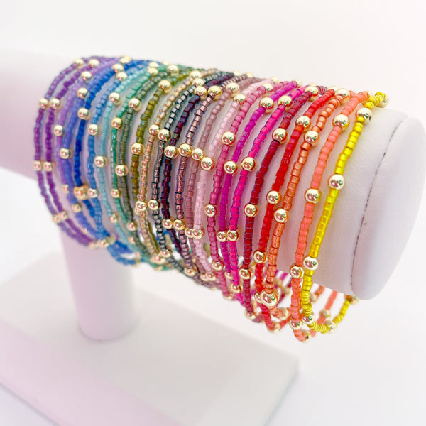 Set of colorful beaded bracelets on a white stand