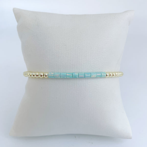 Turquoise opal beaded bracelet with gold accents on a white pillow