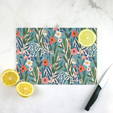 Floral-patterned cutting board with lemons and a knife on a marble surface