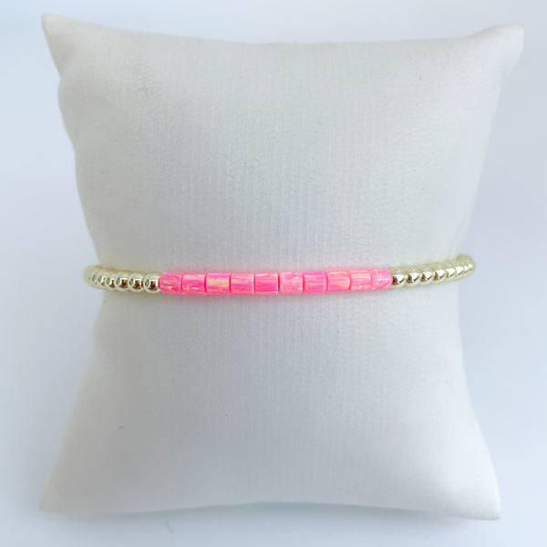 Pink opal beaded bracelet on a white pillow with a white background