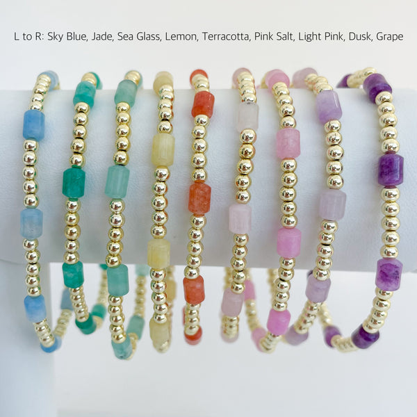 Set of rainbow colored beaded dyed jade bracelets on a bracelet bar with color names.