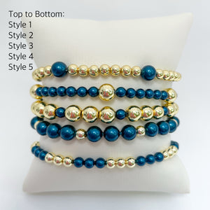 Set of peacock blue austrian crystal pearls and gold beaded bracelets on a white display.