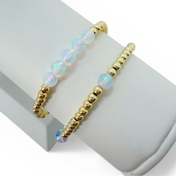Gold beaded bracelet with opal beads on a white surface