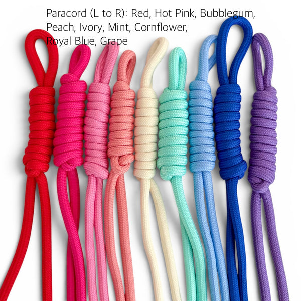 Seven paracord rope ends in different colors arranged vertically on a white background, with text at the top listing the color names: Red, Hot Pink, Bubblegum, Peach, Ivory, Mint, Cornflower, Royal Blue, and Grape.
