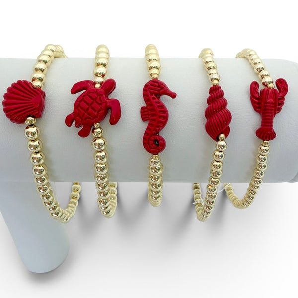 Set of five bracelets with red sea creature charms on a white background