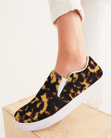 Tortoiseshell patterned slip-on shoes with white soles on a light background